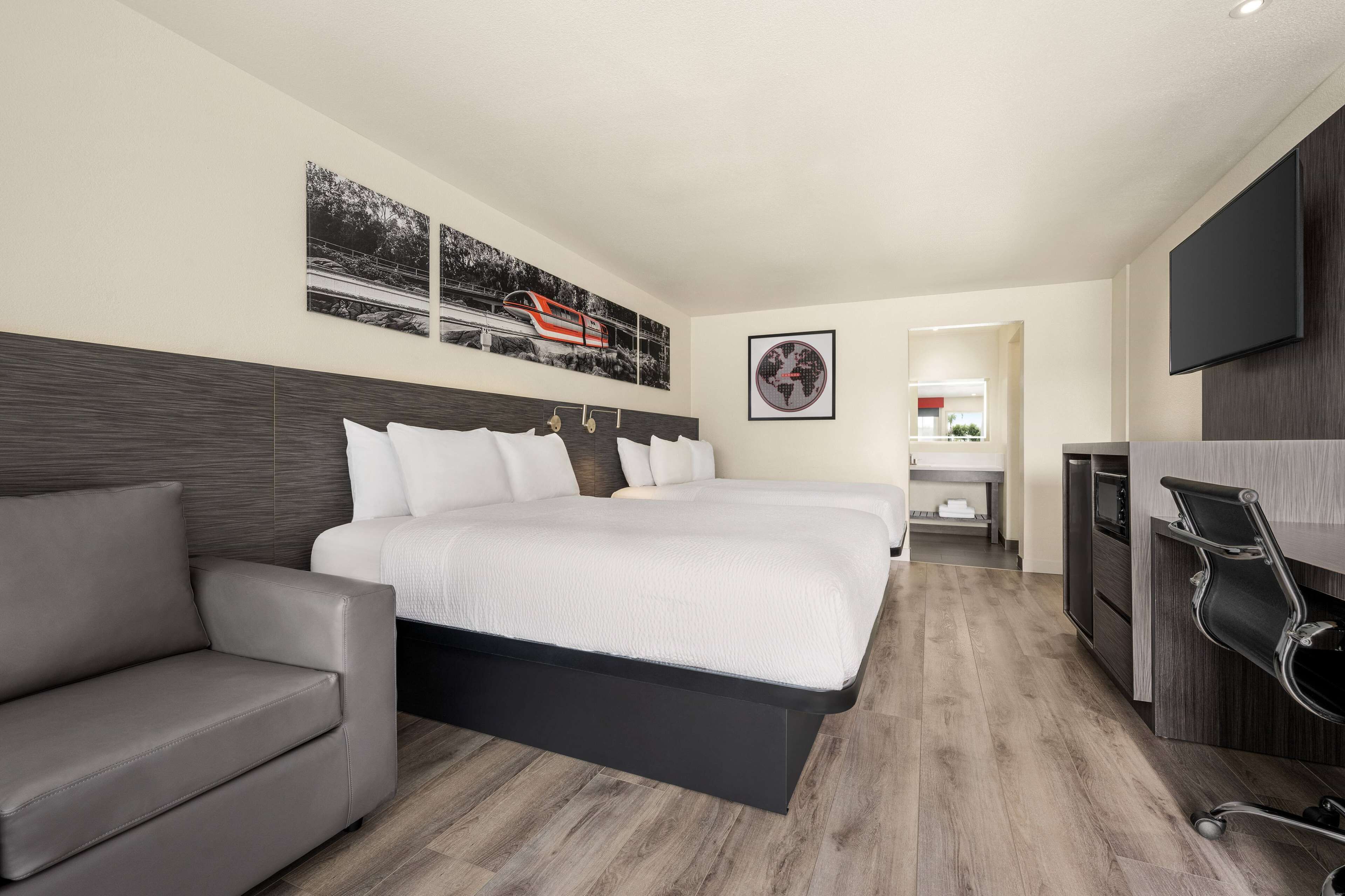 Una habitación de hotel moderna con una cama grande, un sofá, un escritorio y un televisor de pantalla plana.