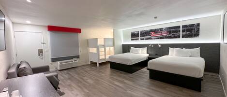 A modern hotel room with two beds, a desk, and a seating area.