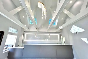 A modern hotel lobby with a high ceiling, geometric ceiling design, and natural light from large windows. - Ramada by Wyndham Anaheim Convention Center (Anaheim)