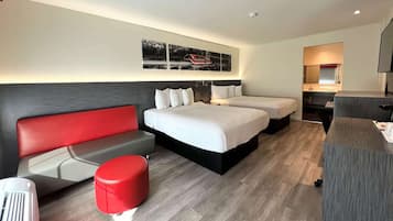 Una habitación de hotel moderna con una cama grande, un sofá rojo, un reposapiés pequeño rojo y un escritorio con espejo.