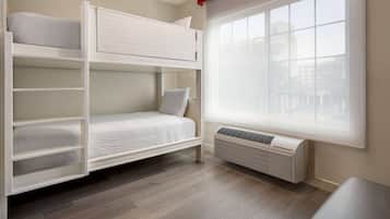 Habitación con literas, ventana y unidad de aire acondicionado.