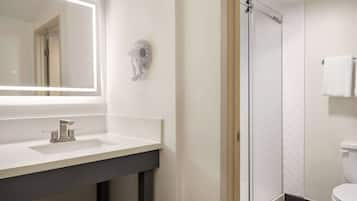 Une salle de bain avec un miroir, un lavabo et une douche.