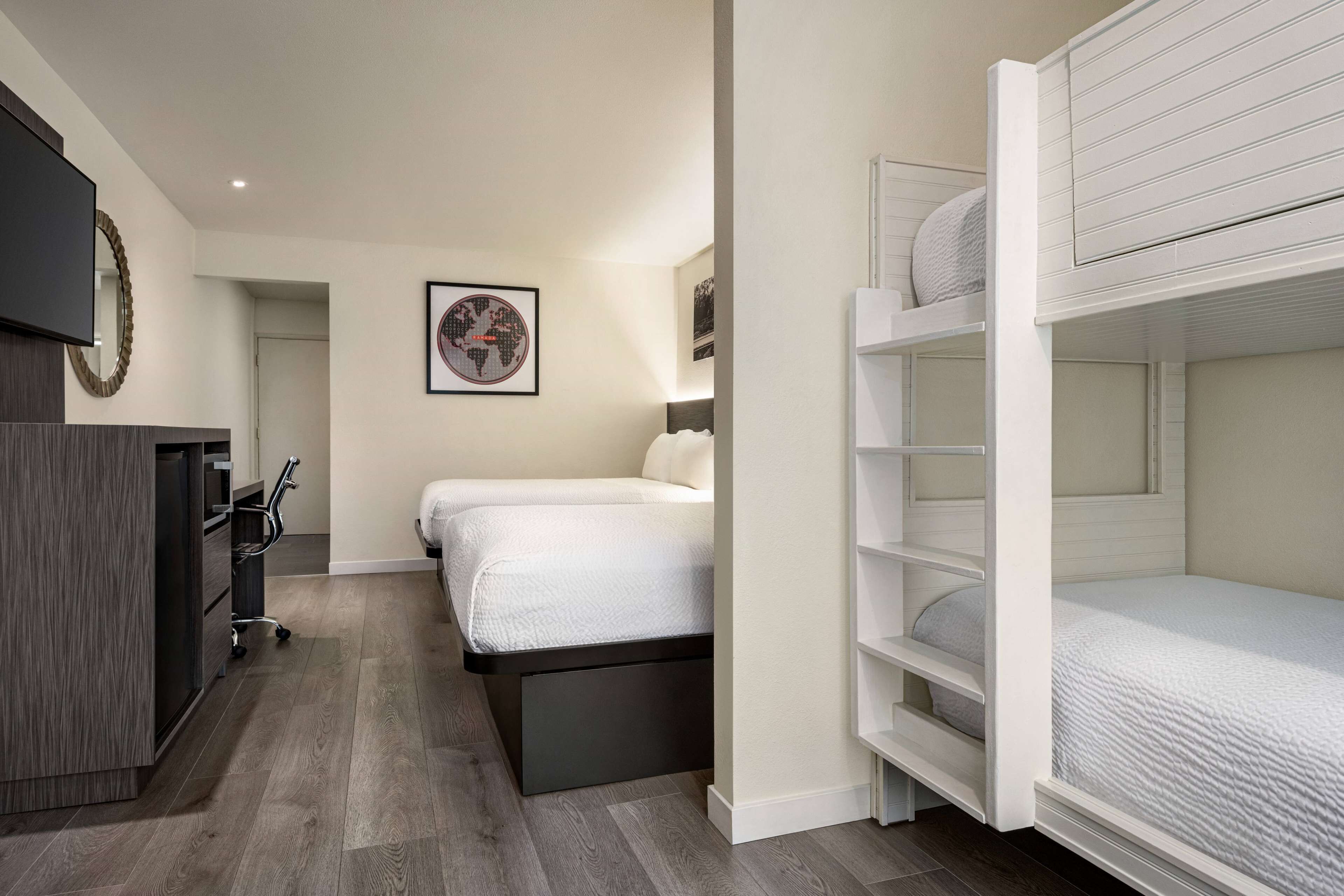 A modern hotel room with a bed, a desk, and a TV.