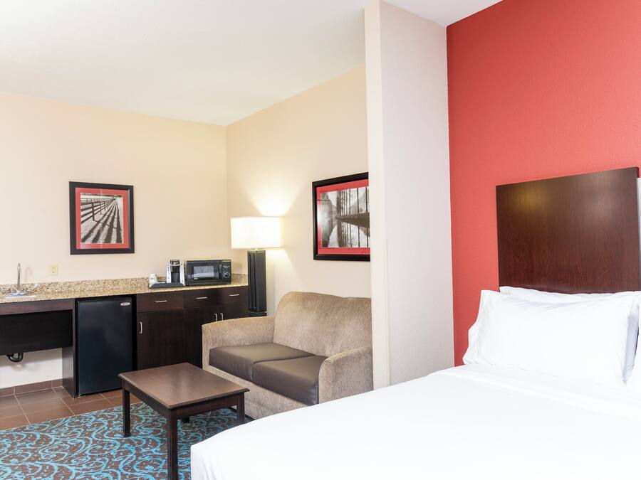 A hotel room with a bed, a desk, a chair, a coffee maker, and a microwave.