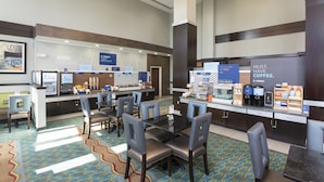 A hotel breakfast area with a coffee station, seating, and a counter with various food items. - Holiday Inn Express Hotel & Suites New Philadelphia by IHG (New Philadelphia)