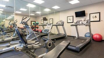 A gym with multiple treadmills, stationary bikes, and exercise balls.