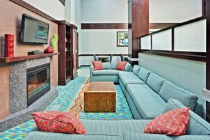 A modern living room with a fireplace, a large sofa set, a coffee table, and a television mounted on the wall.