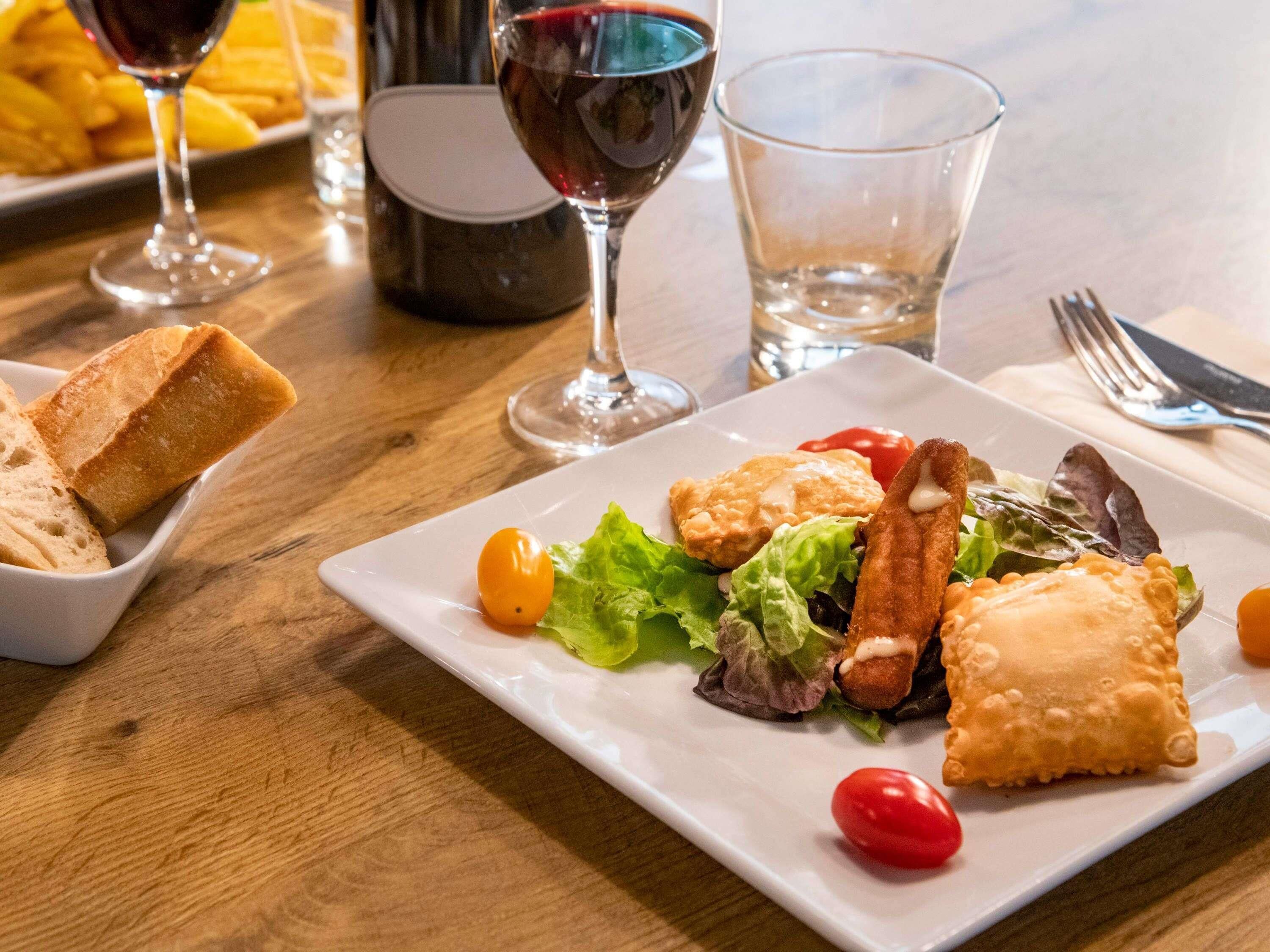 A dining table with a plate of food, a bottle of wine, and glasses.