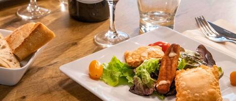 A dining table with a plate of food, a bottle of wine, and glasses.