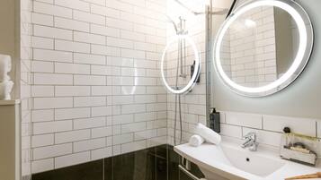 A modern bathroom with white subway tiles, a black tiled shower area, a white sink with a mirror, and a towel rack.