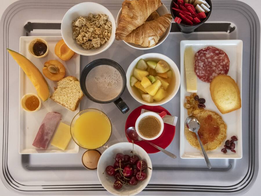A breakfast tray with various food items including toast, fruit, eggs, and pastries.