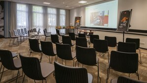 Une salle de conférence avec des rangées de chaises, un écran de projection et des panneaux de présentation.