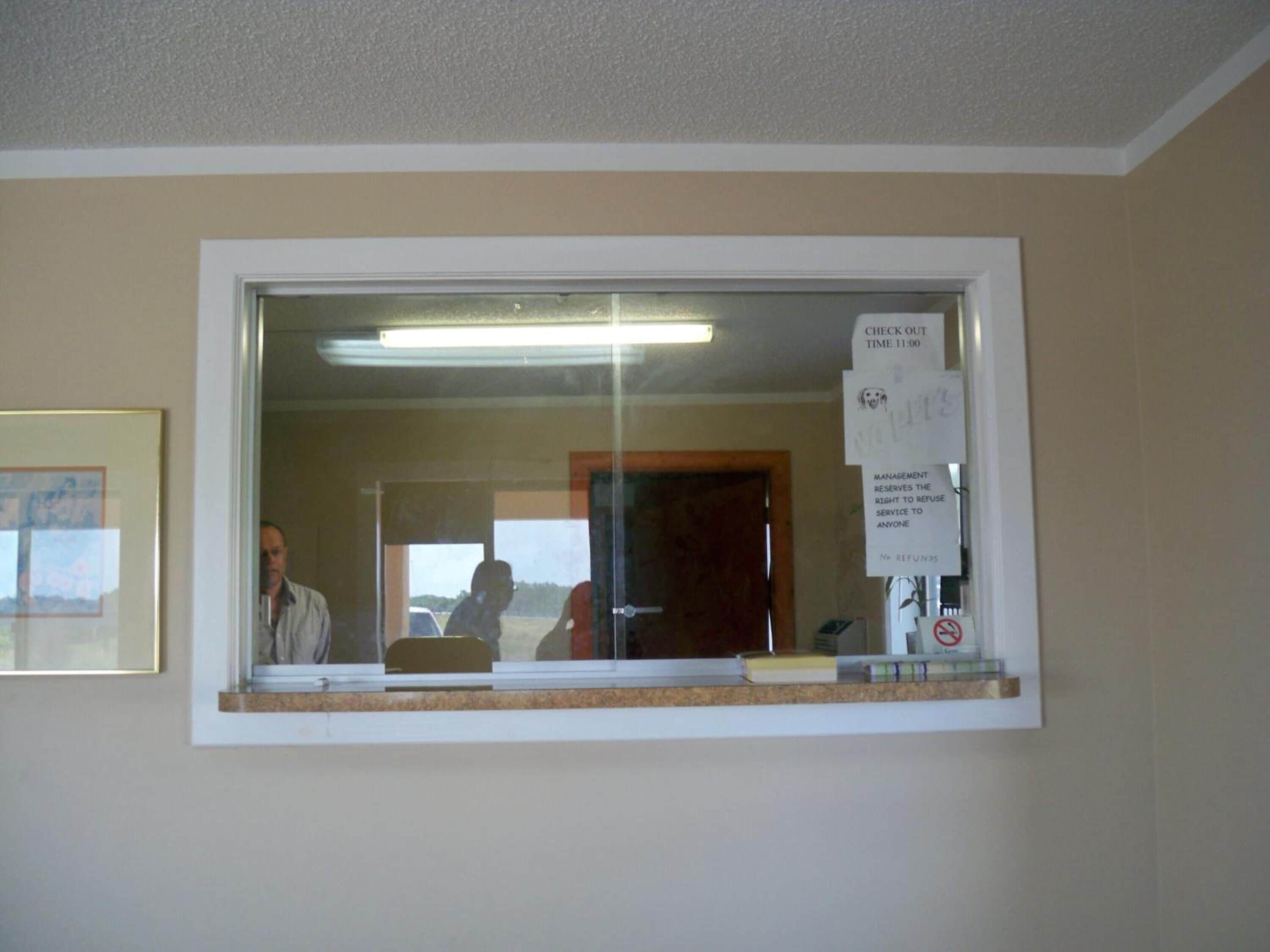 A reception area with a check-out counter, a framed picture on the wall, and a sign indicating check-out time.