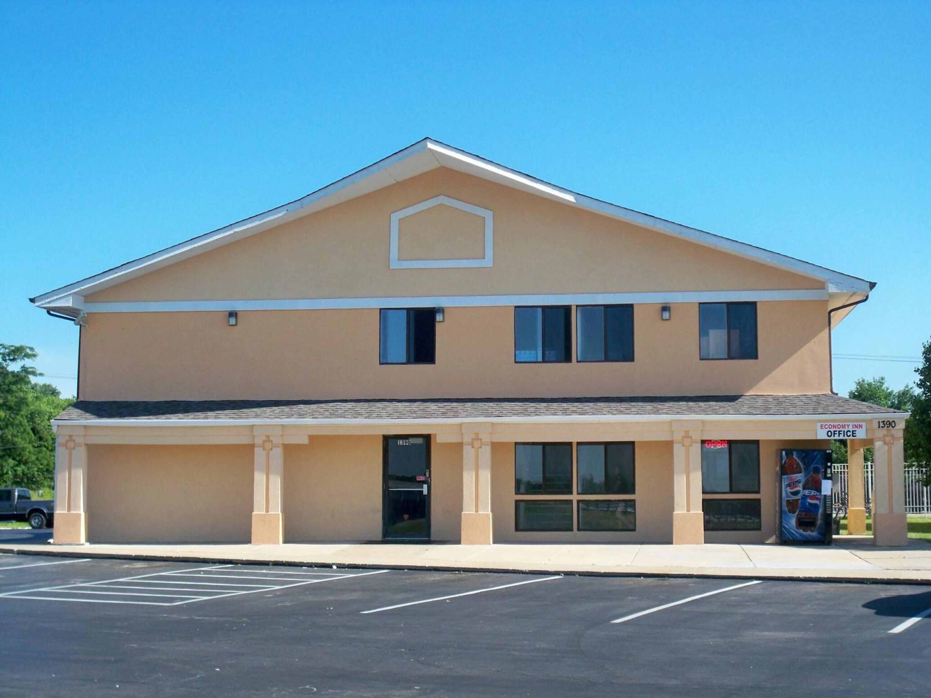 A two-story building with a flat roof, a central entrance, and a sign indicating it is an Economy Inn Office.