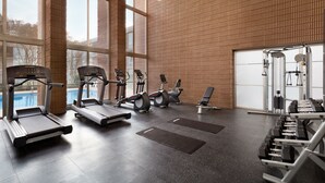 Une salle de sport équipée de tapis de course, de vélos elliptiques et de poids libres.