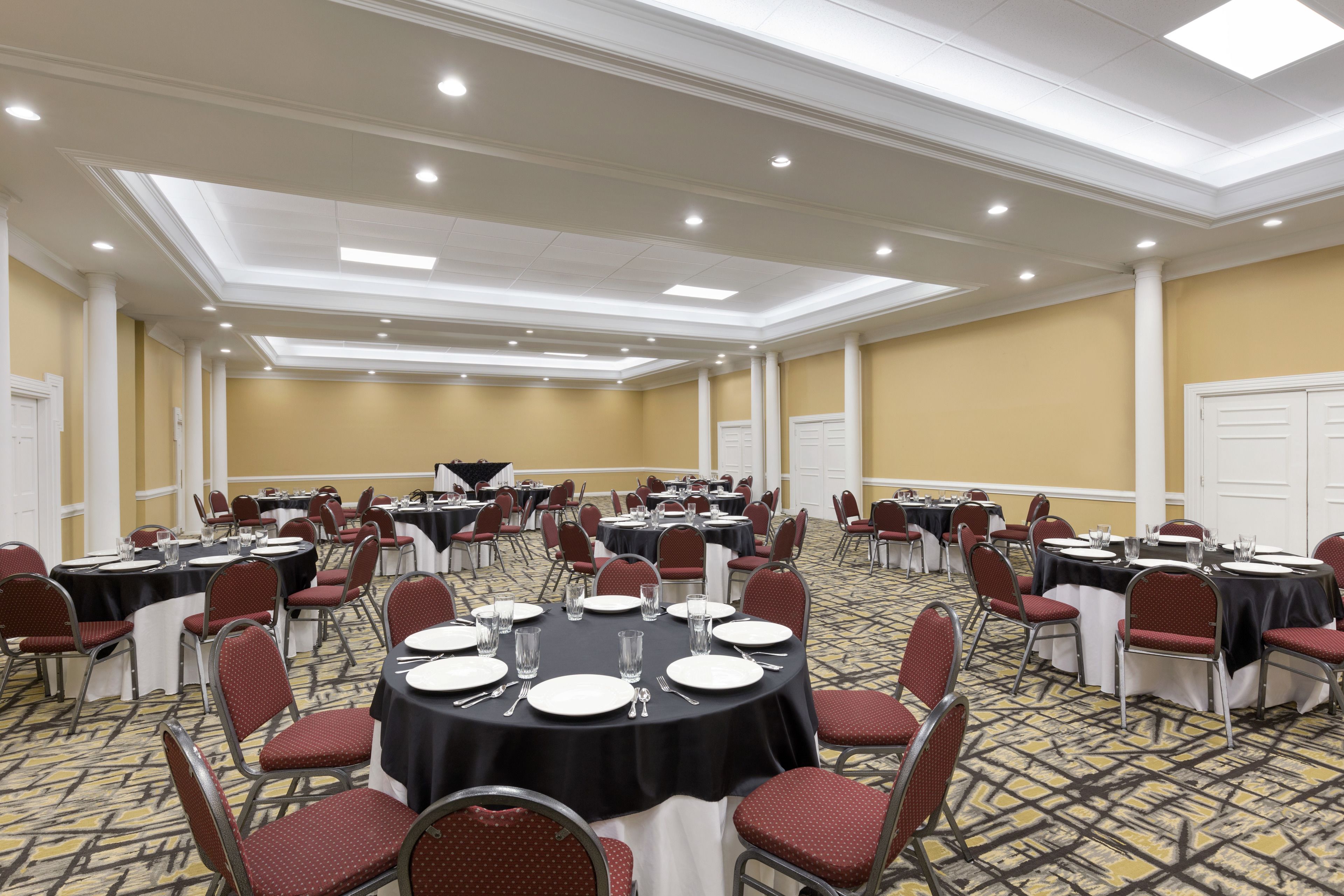 A conference room with round tables, red chairs, and a carpeted floor.