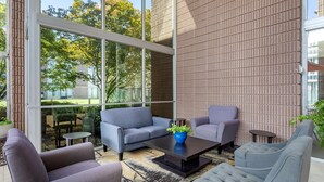 Un espace extérieur moderne, aménagé avec des canapés et une table basse, de grandes fenêtres et un mur en briques.