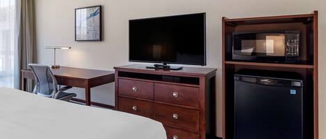 Quarto de hotel com uma cama, uma secretária com televisão de ecrã plano, um micro-ondas e uma cadeira.