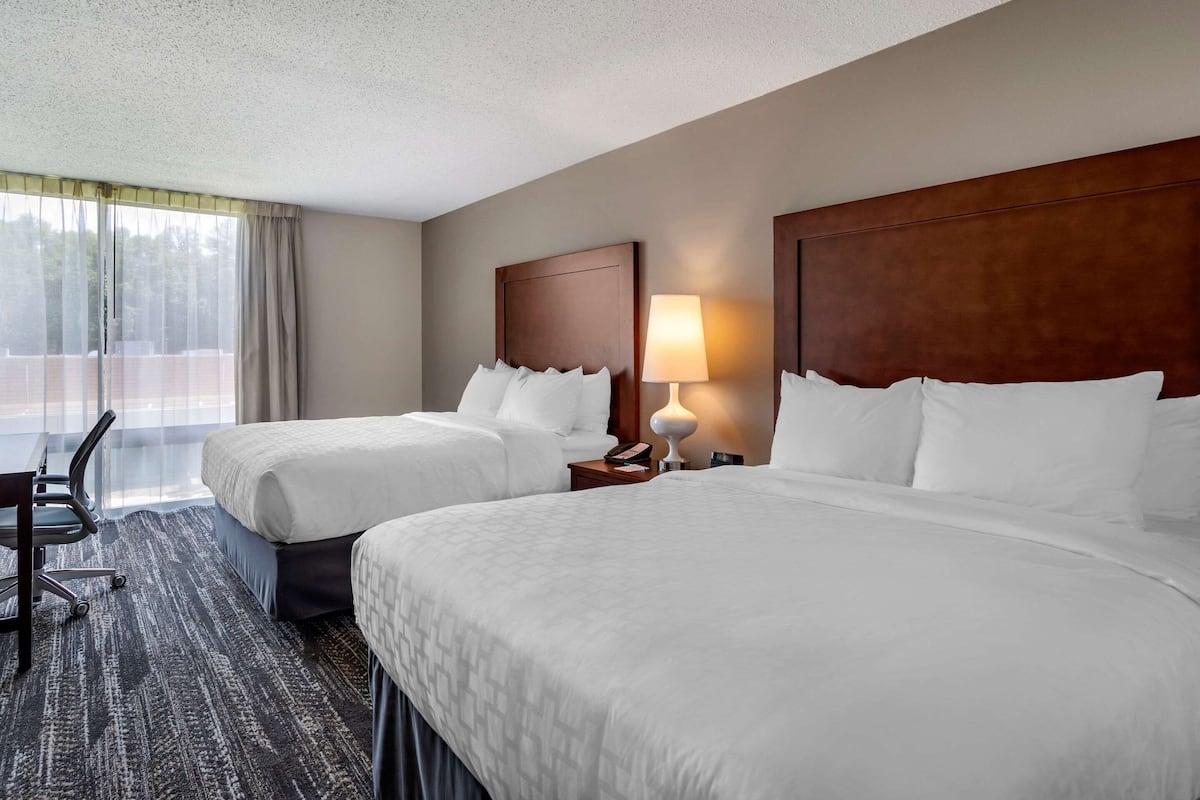 A hotel room with two beds, a desk, and a chair.