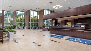 Un hall d’entrée spacieux avec un comptoir de réception, un espace salon et de grandes fenêtres.