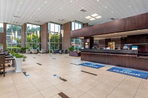 Um hall amplo com balcão de recepção, área de estar e grandes janelas.