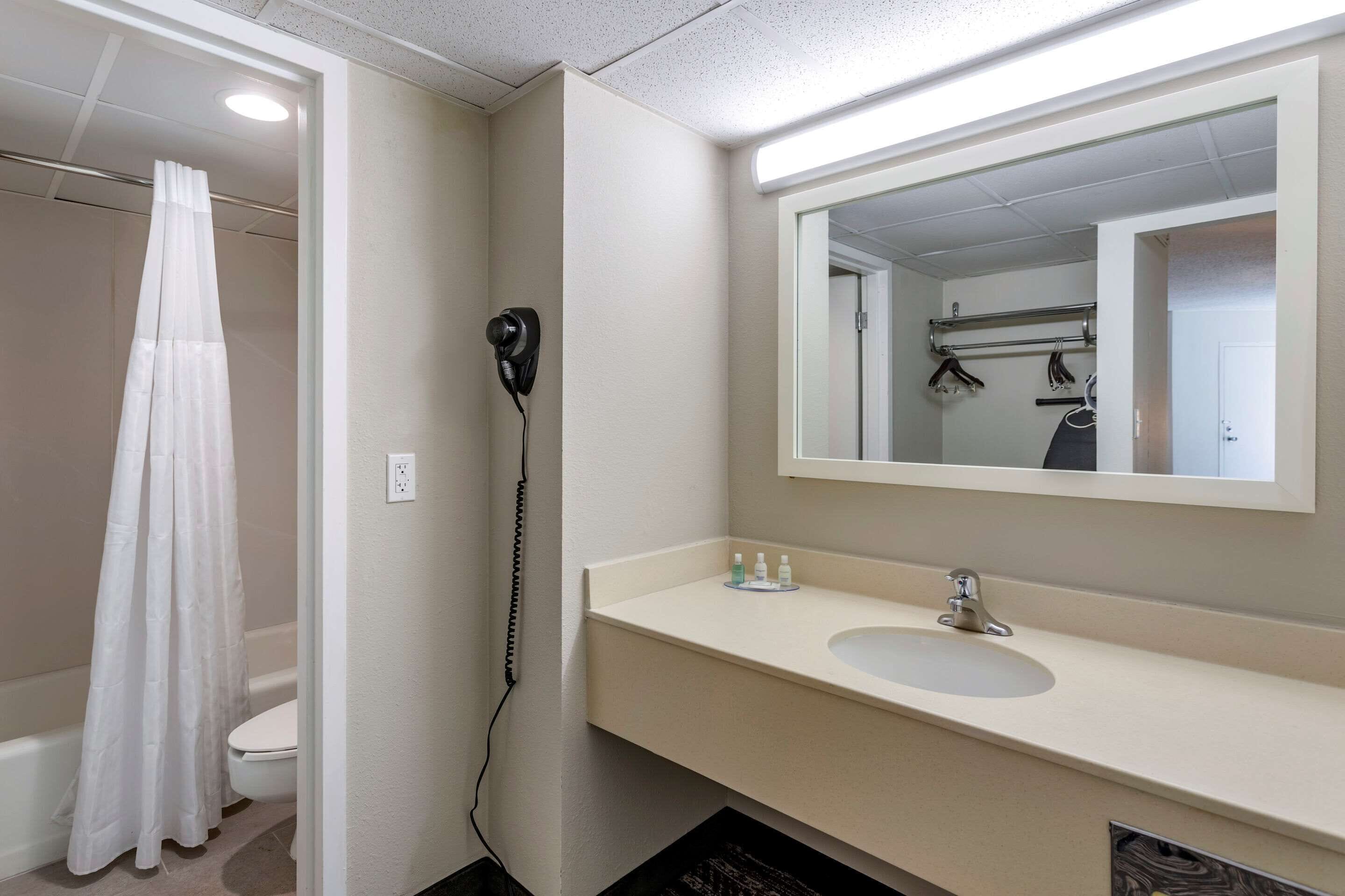 A bathroom with a white sink, mirror, and shower curtain.