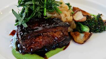 A plate of food with a steak, green vegetables, and a garnish.