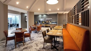A modern dining area with long tables, comfortable seating, and a central kitchen area.