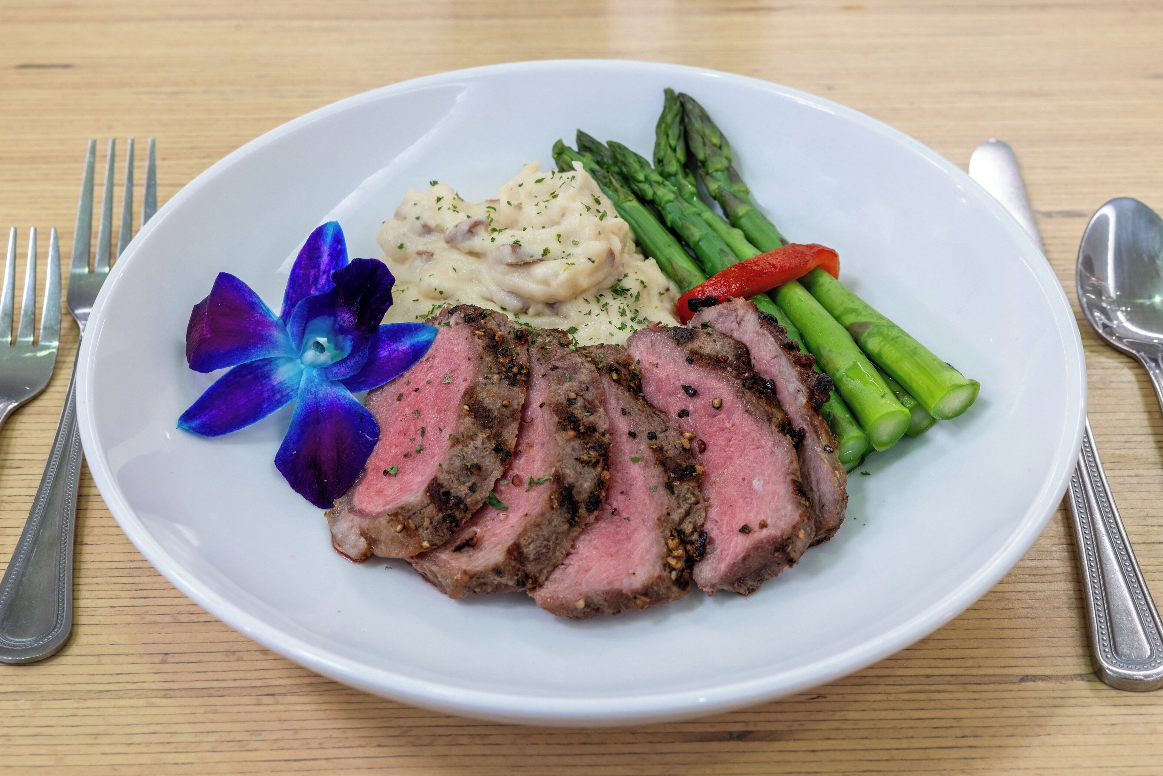 A plate of food with steak, asparagus, and mashed potatoes.