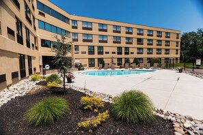 A modern hotel with a swimming pool, landscaped garden, and a multi-story building with numerous windows. - Holiday Inn Philadelphia South - Swedesboro by IHG (Swedesboro)
