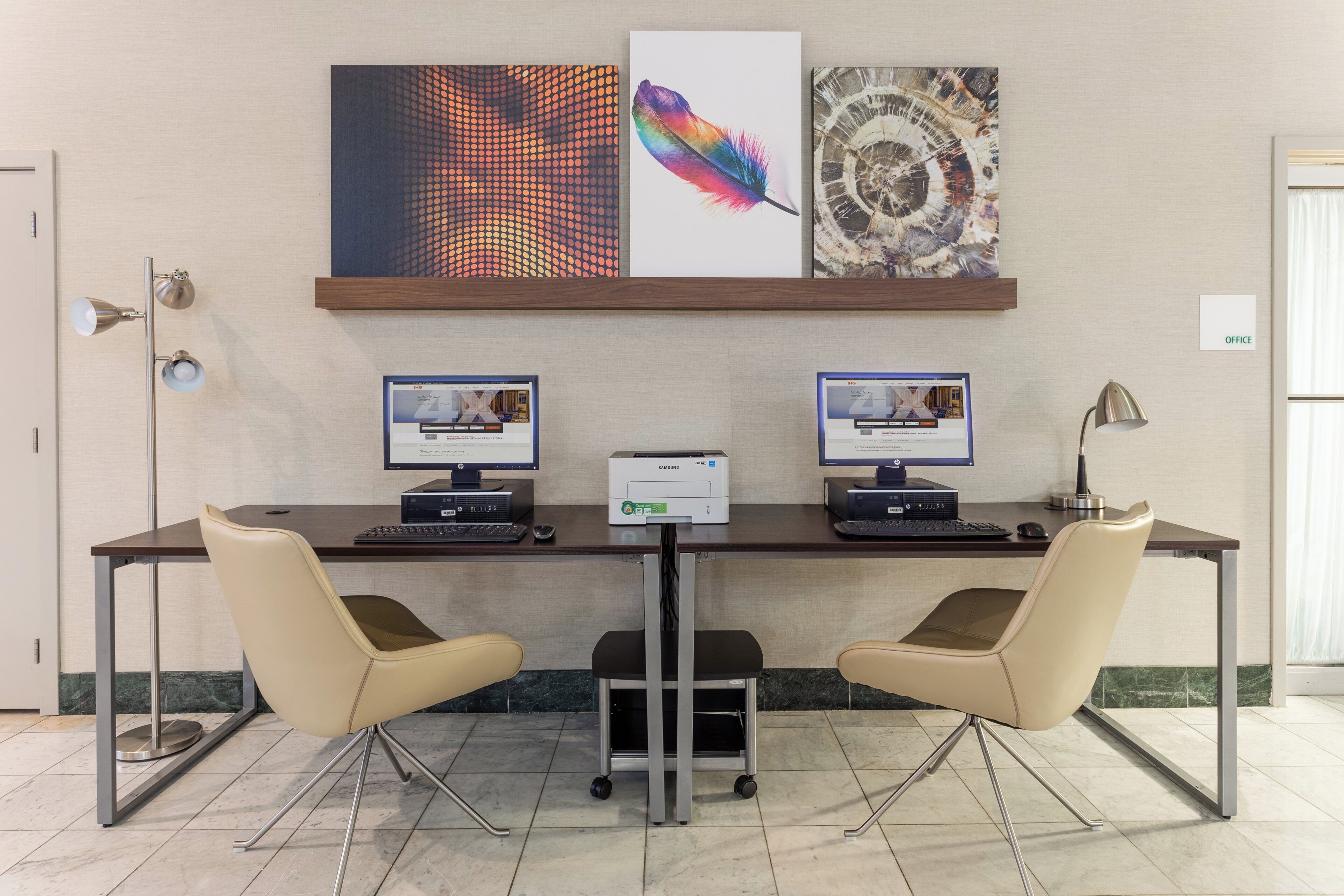 Ein Konferenzraum mit zwei Desktop-Computern, einem Drucker und zwei Stühlen.