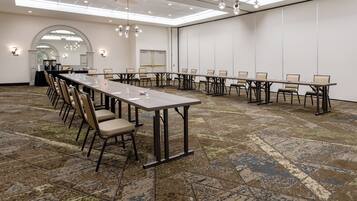 A conference room with a long table, multiple chairs, and a carpeted floor.