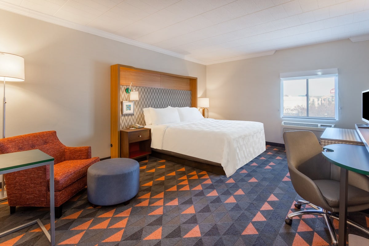 Ein Hotelzimmer mit einem Bett, einem Schreibtisch, einem Sessel, einer Couch und einem kleinen Tisch.