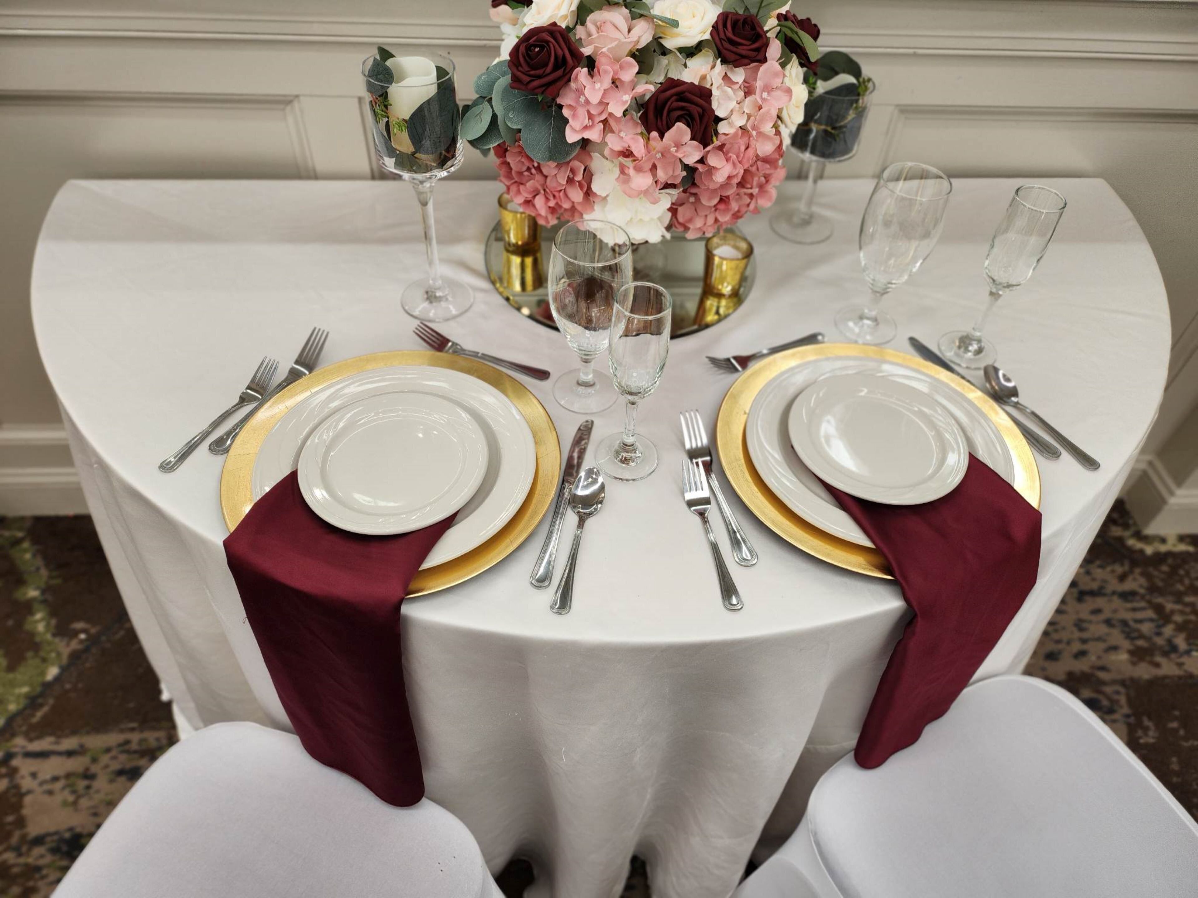 Een tafel gedekt voor twee personen, met witte borden, gouden randen en zilveren bestek.