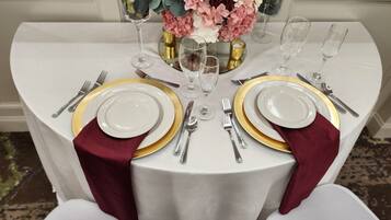 Een tafel gedekt voor twee personen, met witte borden, gouden randen en zilveren bestek.