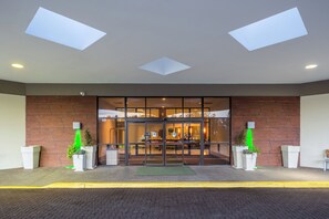 A hotel entrance with a brick facade, large glass doors, and a green mat at the entrance. - Holiday Inn Philadelphia South - Swedesboro by IHG (Swedesboro)
