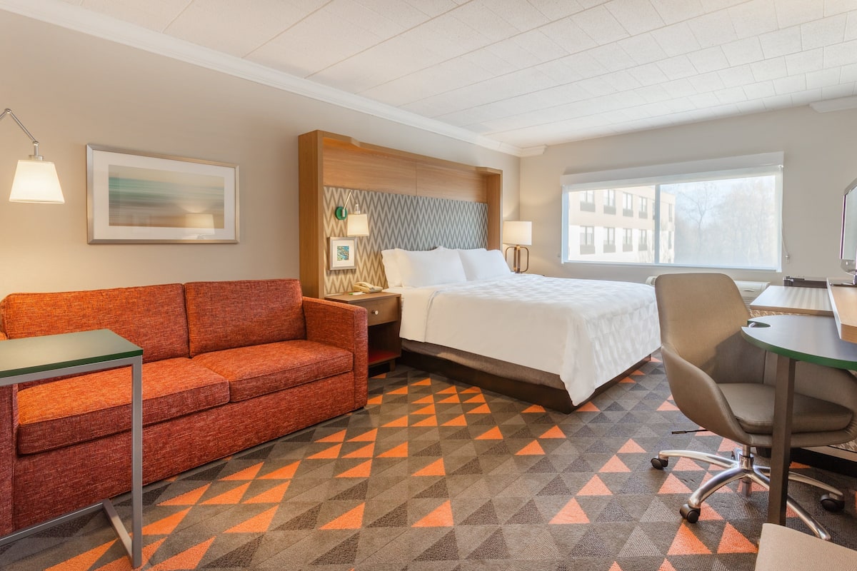 Ein Hotelzimmer mit Bett, Sofa, Schreibtisch und Stuhl.