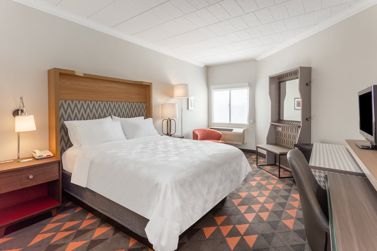 Ein Hotelzimmer mit Bett, Schreibtisch, Stuhl und Fernseher.