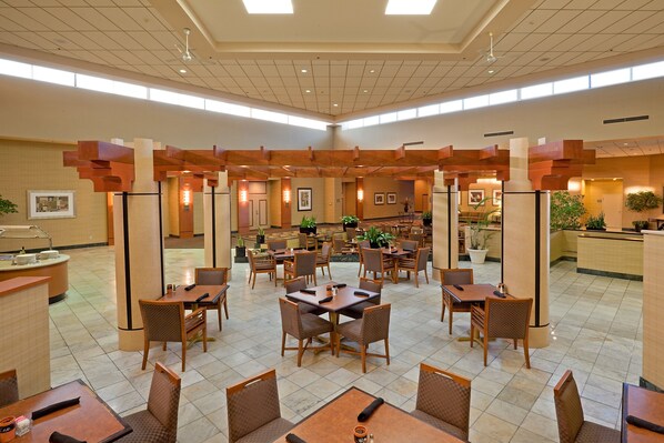 A spacious hotel lobby with multiple dining areas, ceiling fans, and natural light from large windows. - Holiday Inn Philadelphia South - Swedesboro by IHG (Swedesboro)