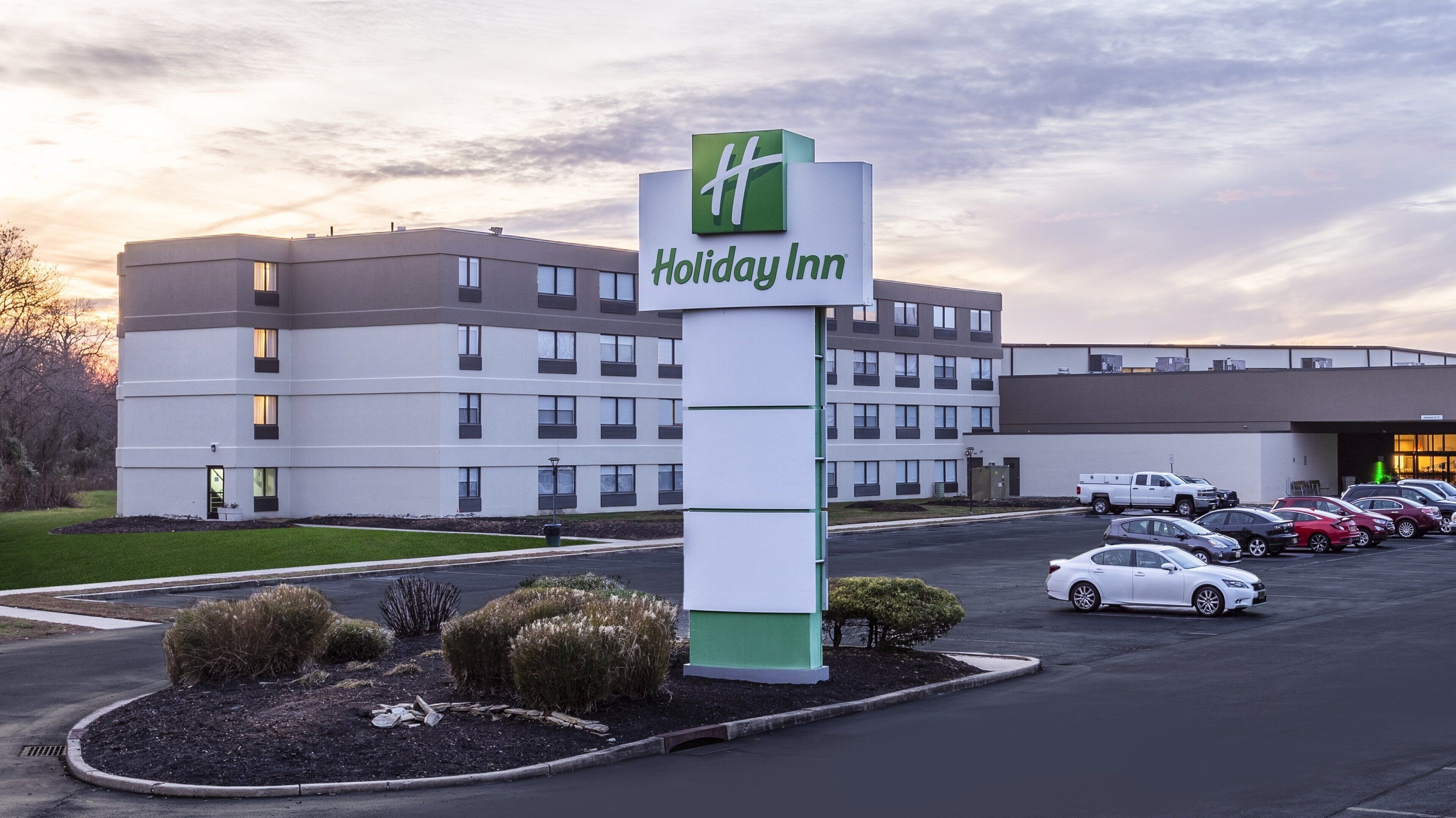 A Holiday Inn hotel with a parking lot and a building with multiple floors and windows.