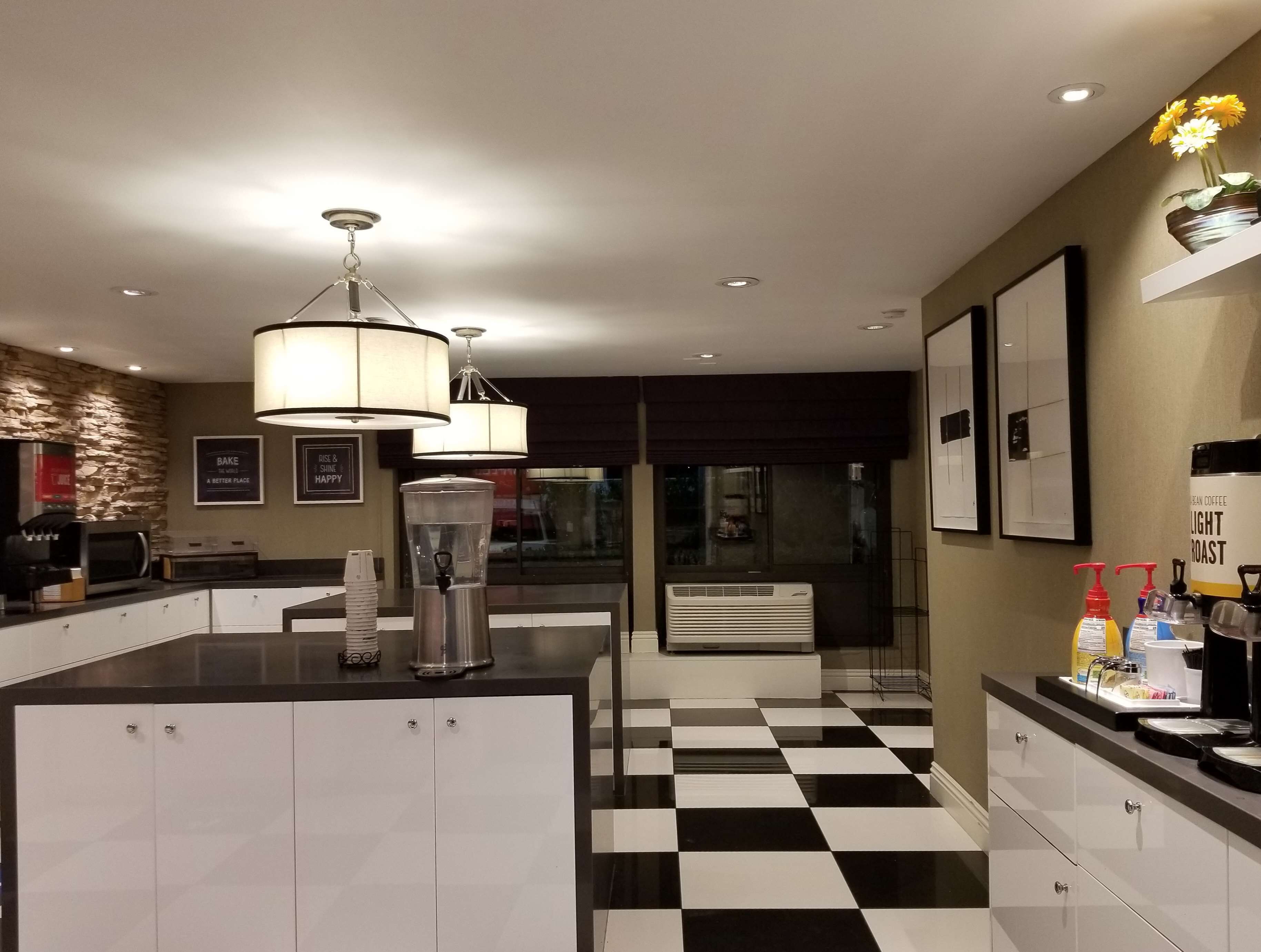 Una cocina moderna con suelo a cuadros, una estación de café y una pared de piedra.