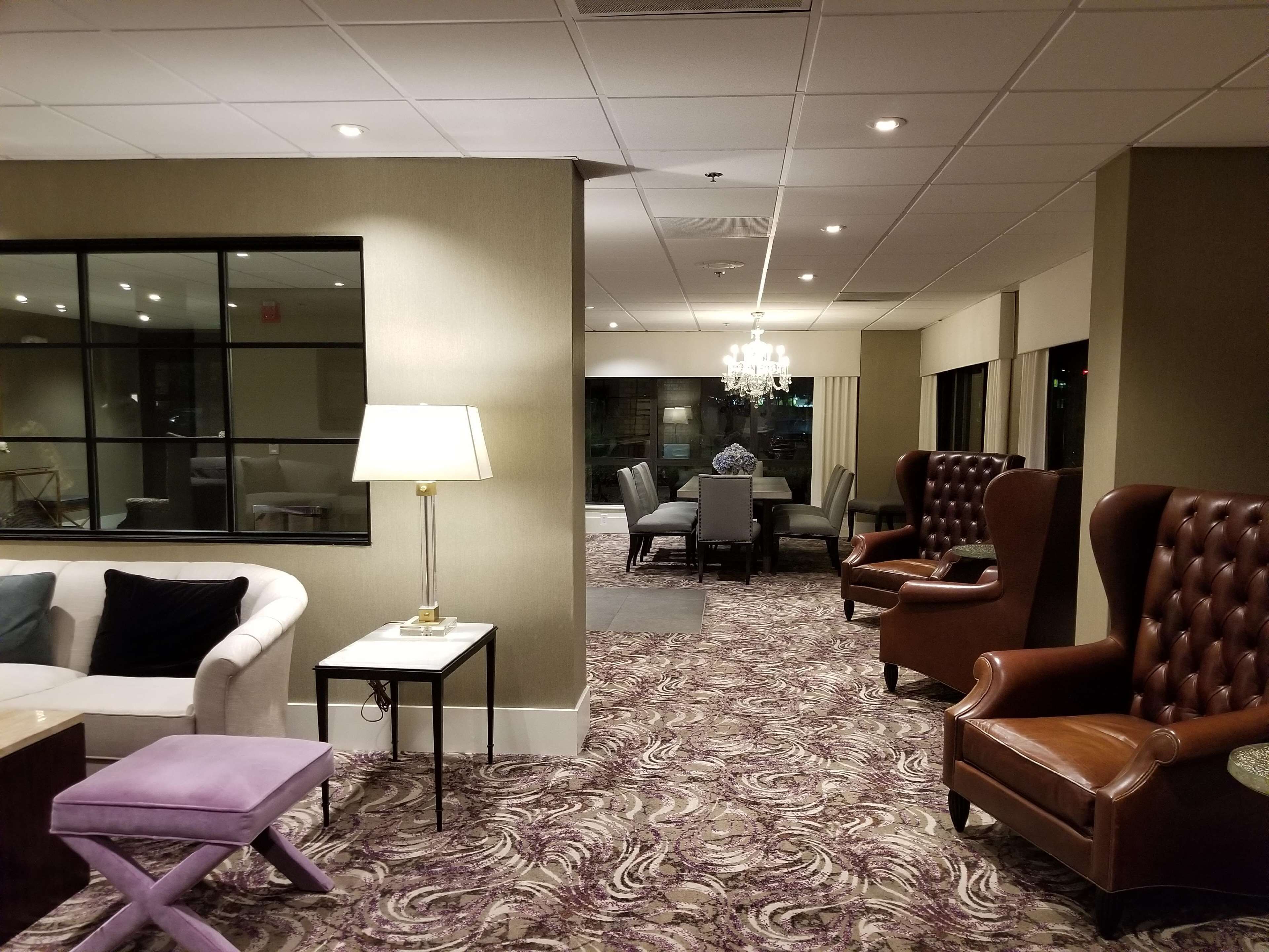 Un vestíbulo de hotel con zona de estar, una araña y un comedor al fondo.