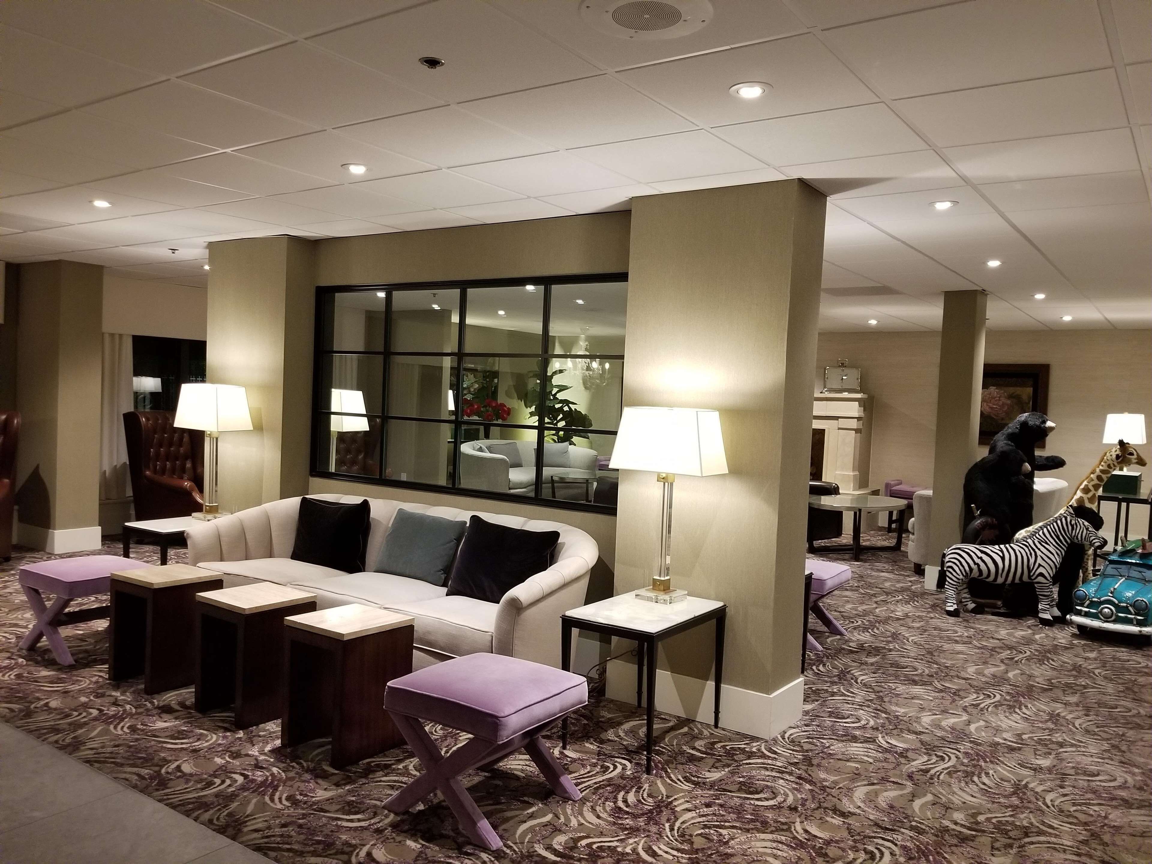 A hotel lobby with a sofa, armchairs, a coffee table, and a patterned carpet.