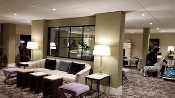 A hotel lobby with a sofa, armchairs, a coffee table, and a patterned carpet.
