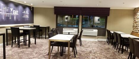 A conference room with a large projection screen, multiple tables and chairs, and a patterned carpet.
