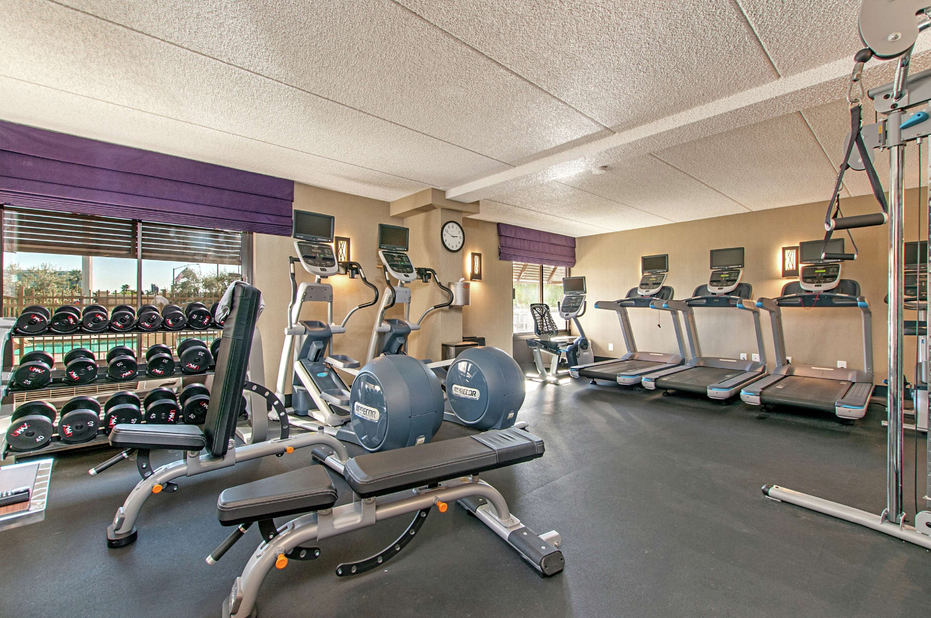 Une salle de sport équipée de tapis de course, de vélos elliptiques et de poids libres.