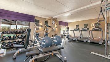 Une salle de sport équipée de tapis de course, de vélos elliptiques et de poids libres.