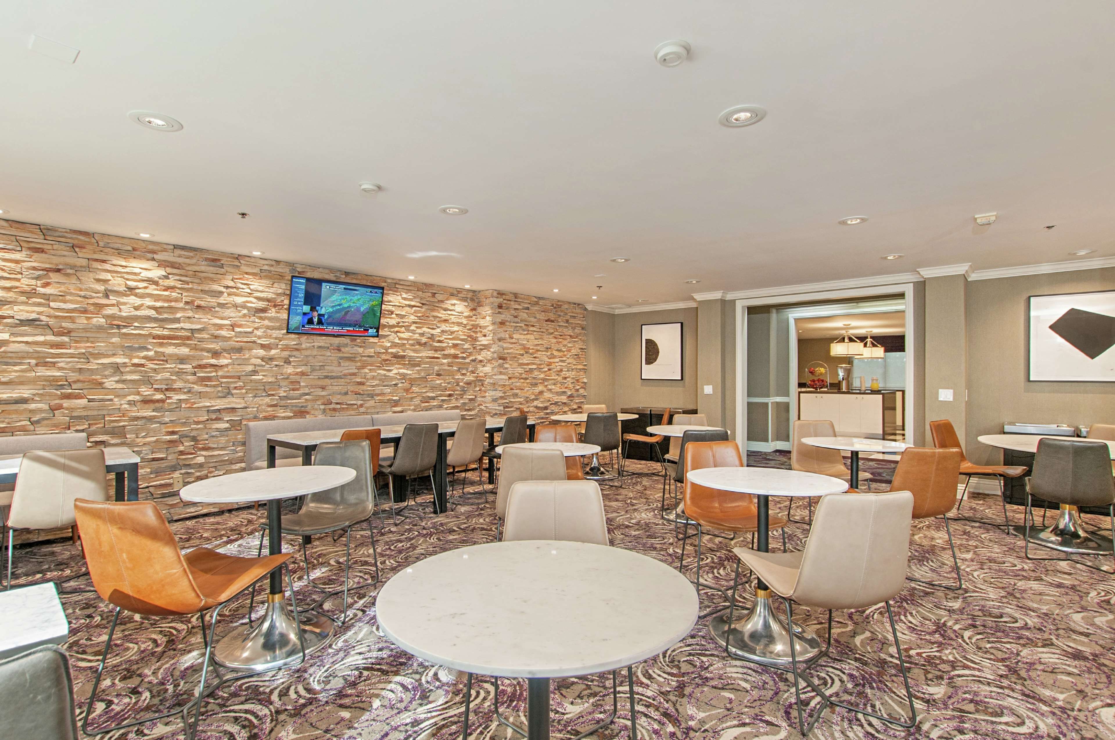 A hotel lobby with stone walls, multiple seating areas, and a television screen.