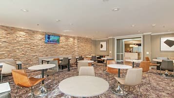 A hotel lobby with stone walls, multiple seating areas, and a television screen.