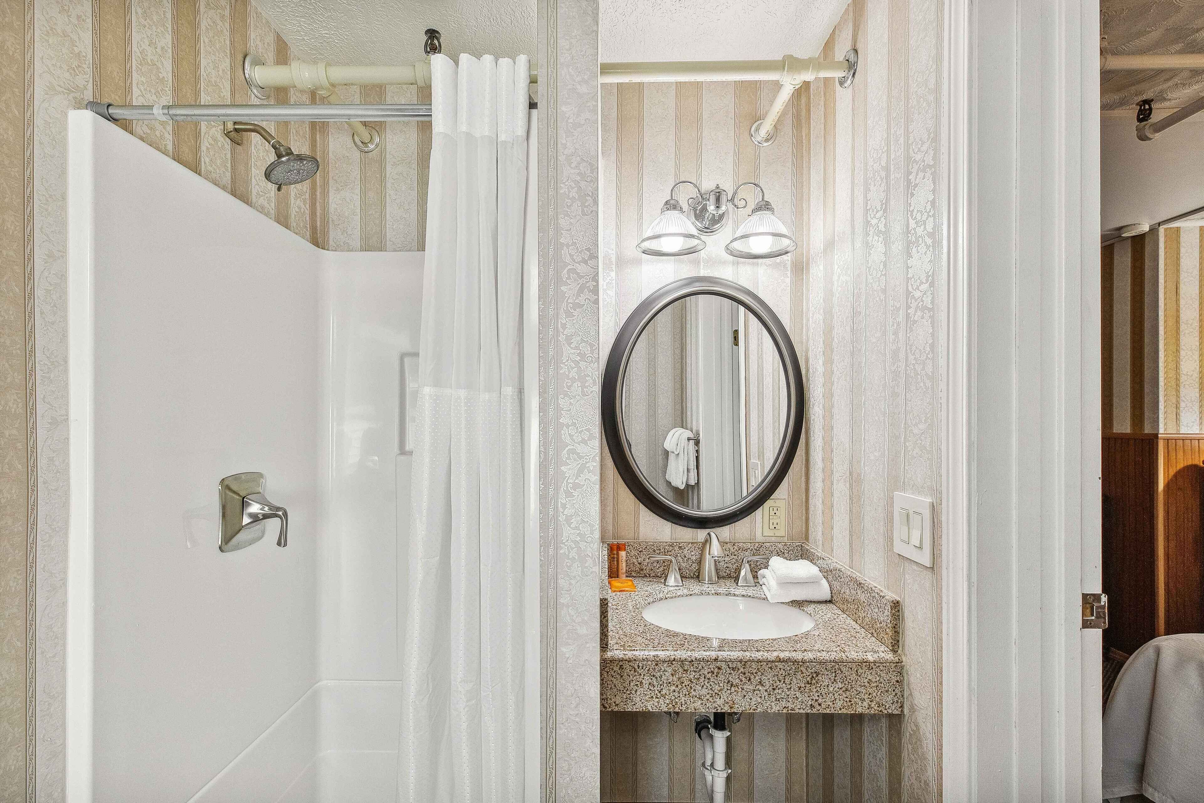 A bathroom with a shower, a sink with a mirror, and a towel rack.
